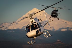 two helicopters flying past mt. hood