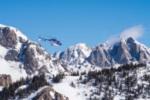 helicopter flying through snowy mountains