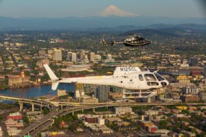 two helicopters flying over portland with mt. hood in background