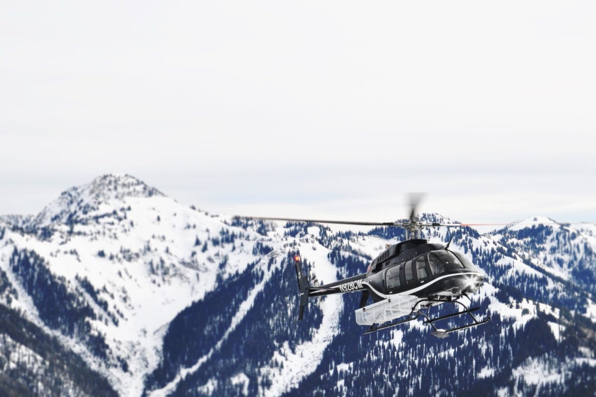 helicopter flying over snowy mountains