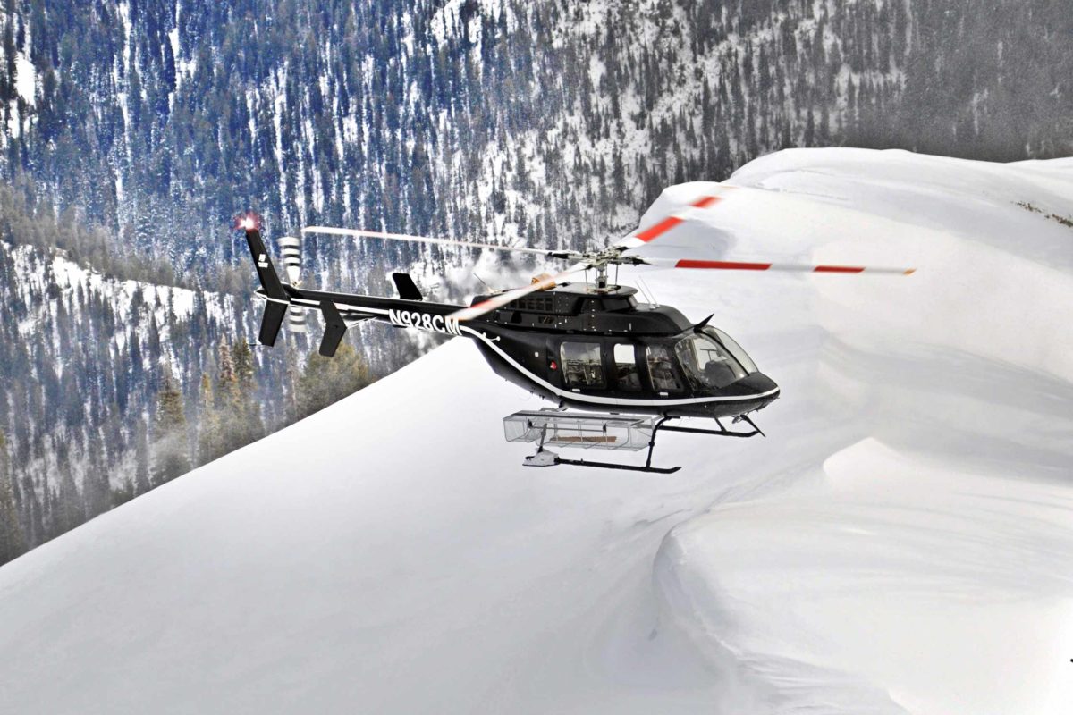 helicopter flying over snowy mountain terrain